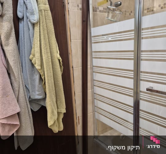 דלת עץ עם מגבות תלויים ומקלחון זכוכית